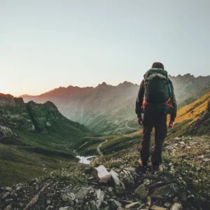 Man hiking at sunset mountains with heavy backpack Travel Lifestyle wanderlust adventure concept summer vacations outdoor alone into the wild